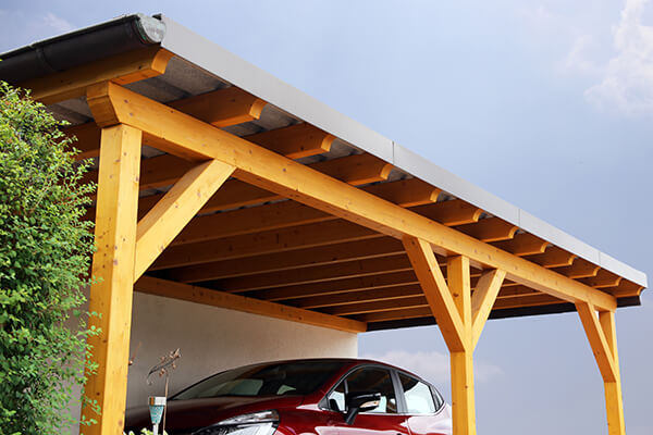 Carport en bois avec voiture rouge